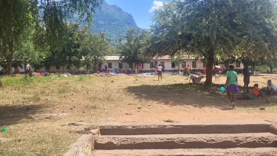 The schoolyard under shade trees, hills beyond